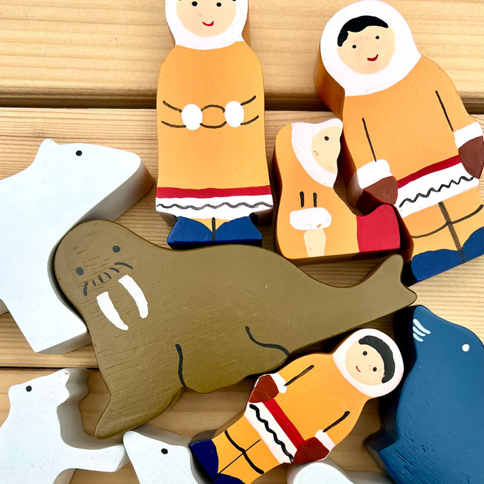 Wooden toys depicting Inuit people and animals on a wooden surface