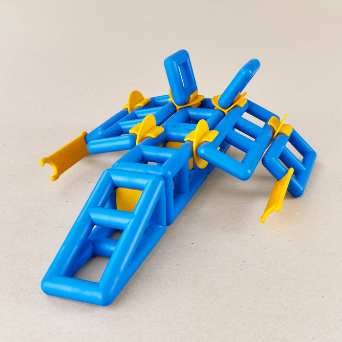 A blue and yellow magnetic building toy structure made of interlocking plastic connectors, photographed on a plain light beige background.