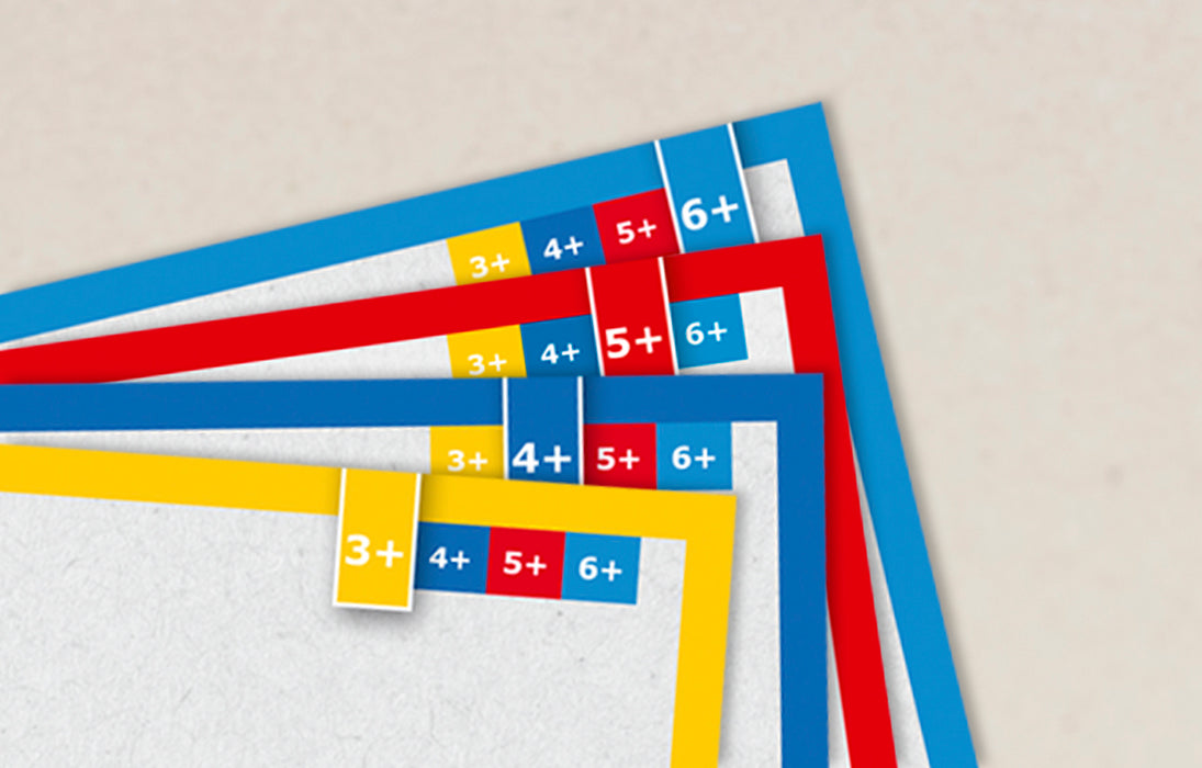 A close-up of overlapping paper strips with colored borders and printed age labels such as 3+, 4+, 5+, and 6+ on a light beige background.