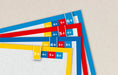 A close-up of overlapping paper strips with colored borders and printed age labels such as 3+, 4+, 5+, and 6+ on a light beige background.